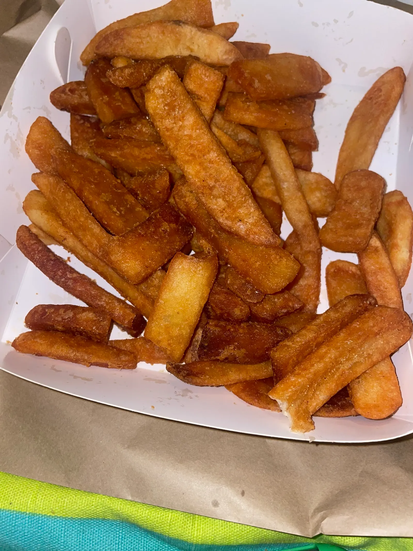 Golden crispy chips in a white cardboard chip tray, close-up overhead shot